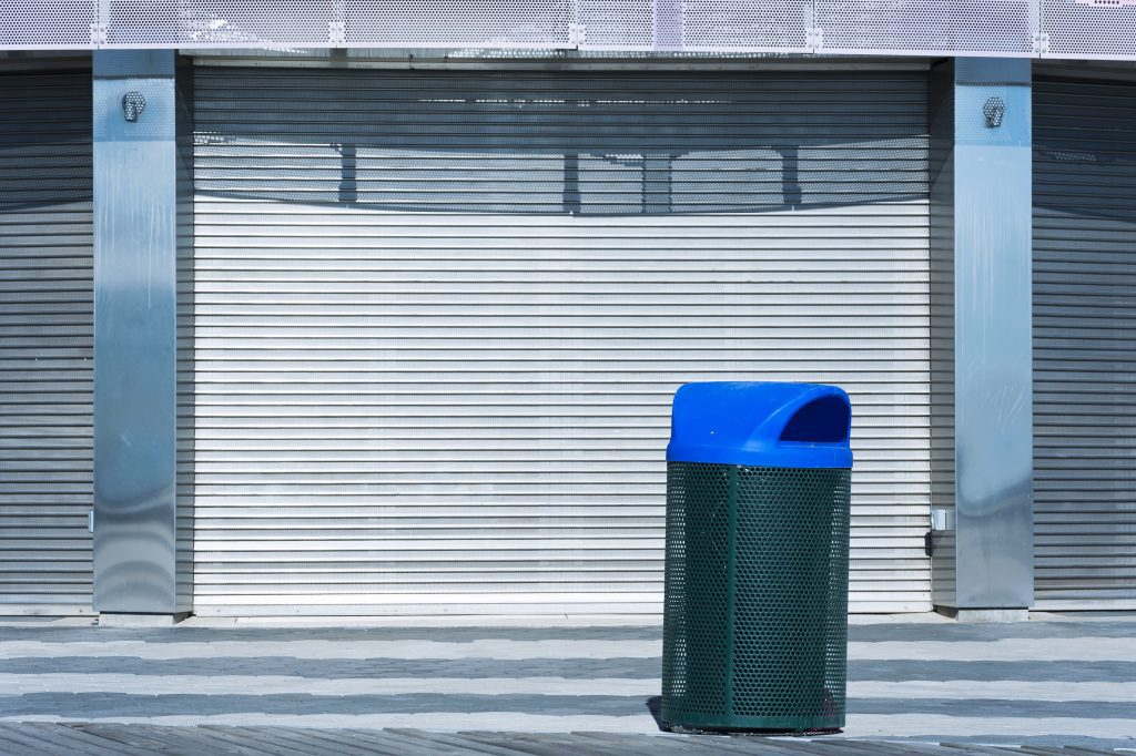 Blue trash can in front of closed door, with shutter won't stay up open, common roller shutter problems.